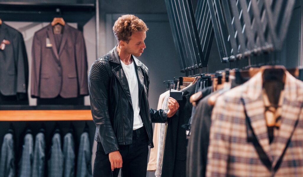 Young guy in modern store with new clothes. Elegant expensive wear for men